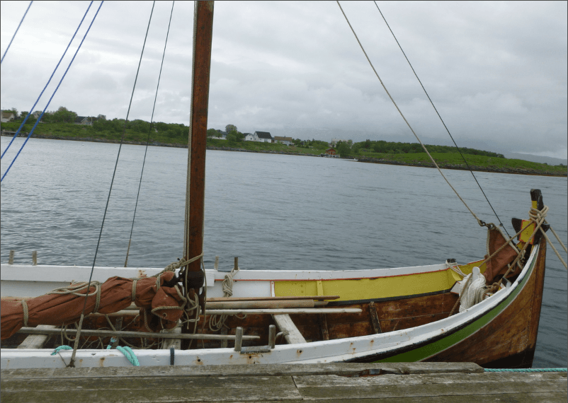 Restored Nordland firroring Enigheten moored beside a quay with its mast, rigging and painted wooden hull visible