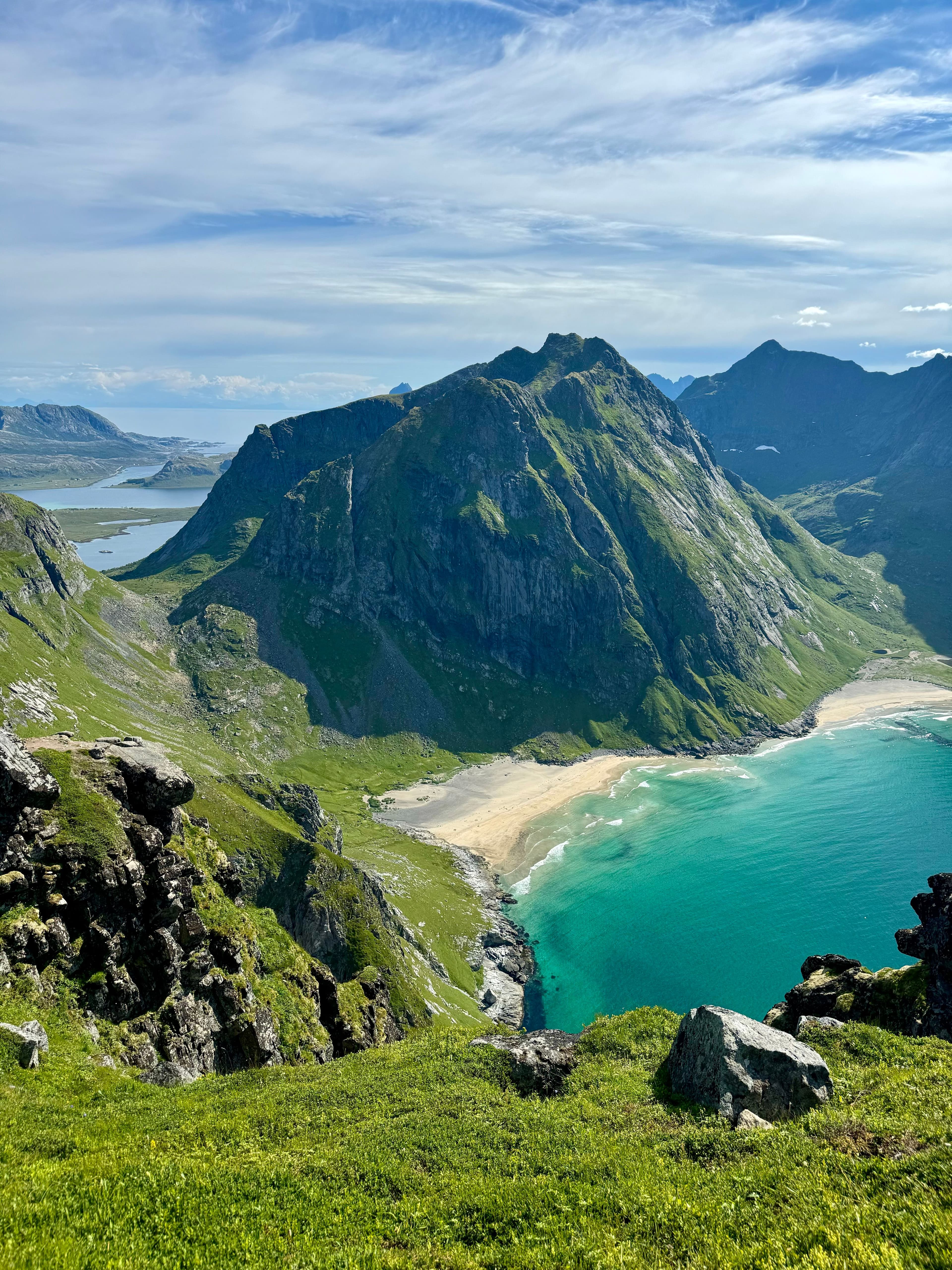 A mountain rising above a pale Norwegian beach and sea