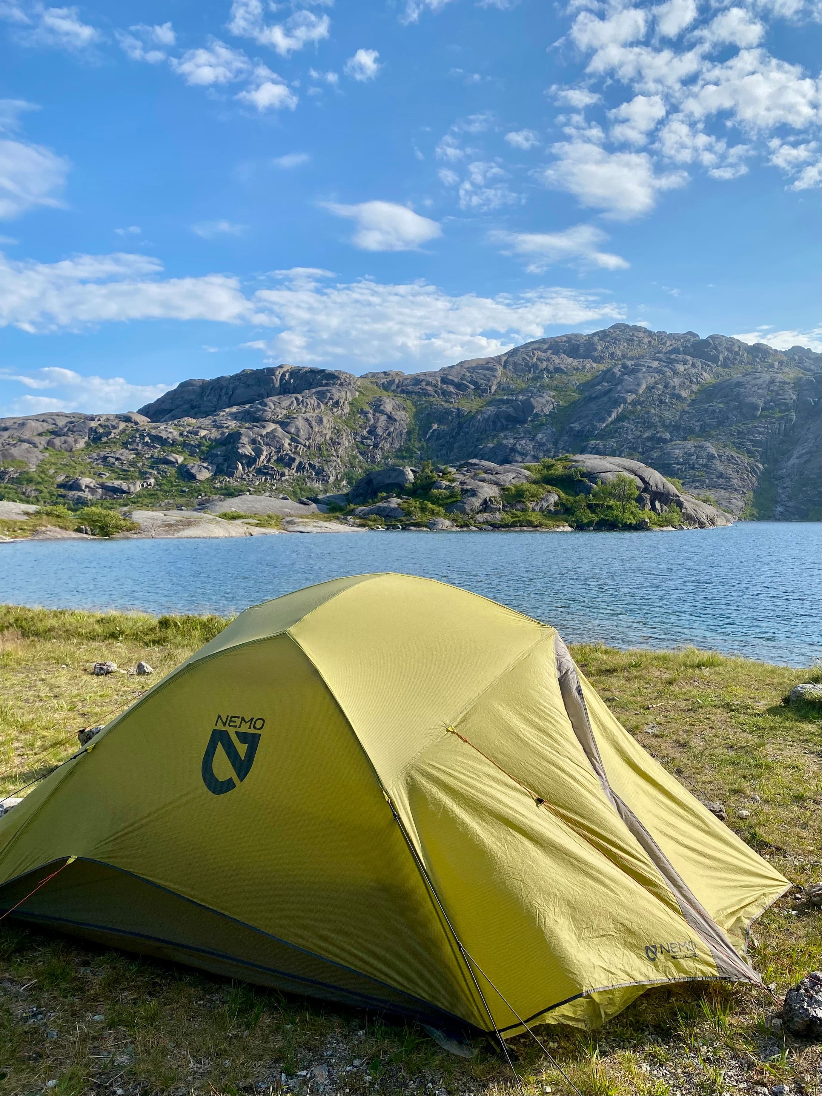 A yellow tent beside a mountain lake in Norway