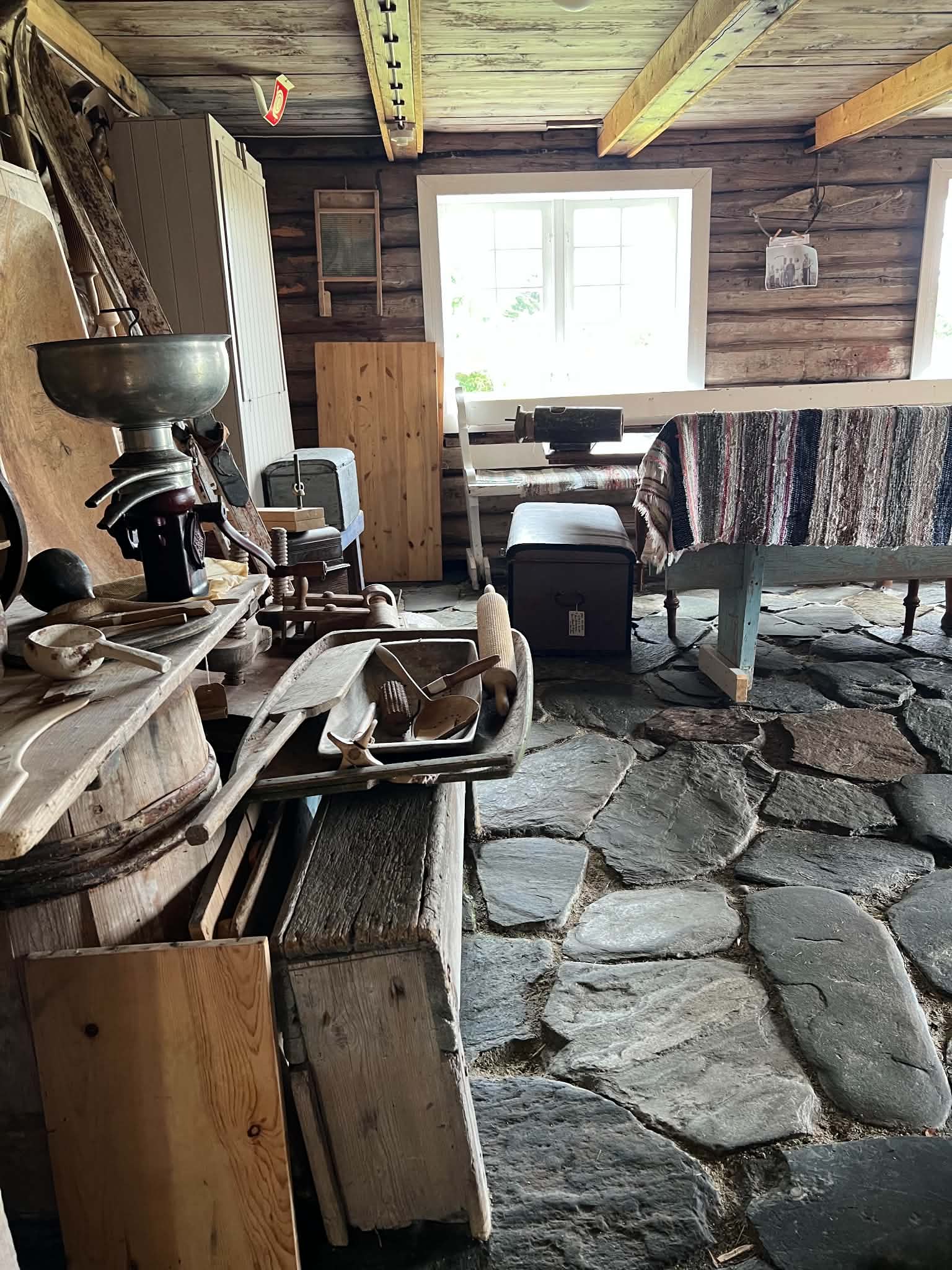 Wooden workroom with traditional clothing, textiles and storage chests