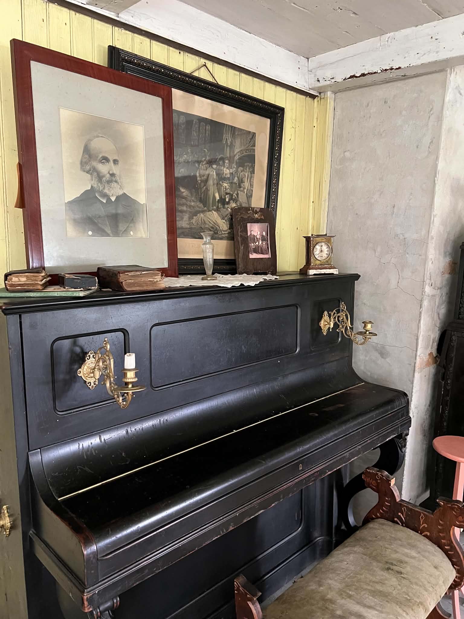 Black upright piano with portraits and household objects