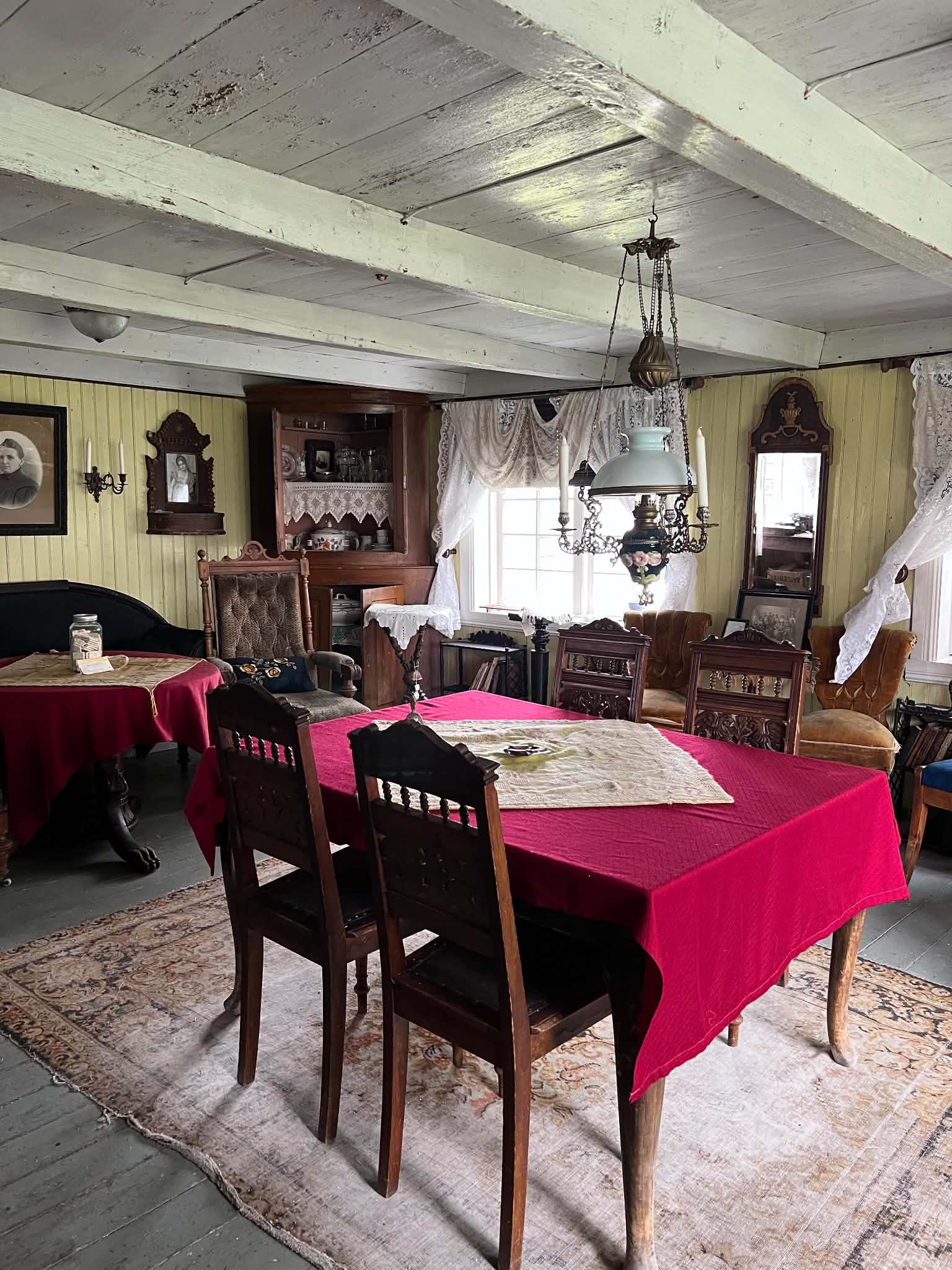 Preserved coastal sitting room with red tablecloths and historic furniture in Helgeland