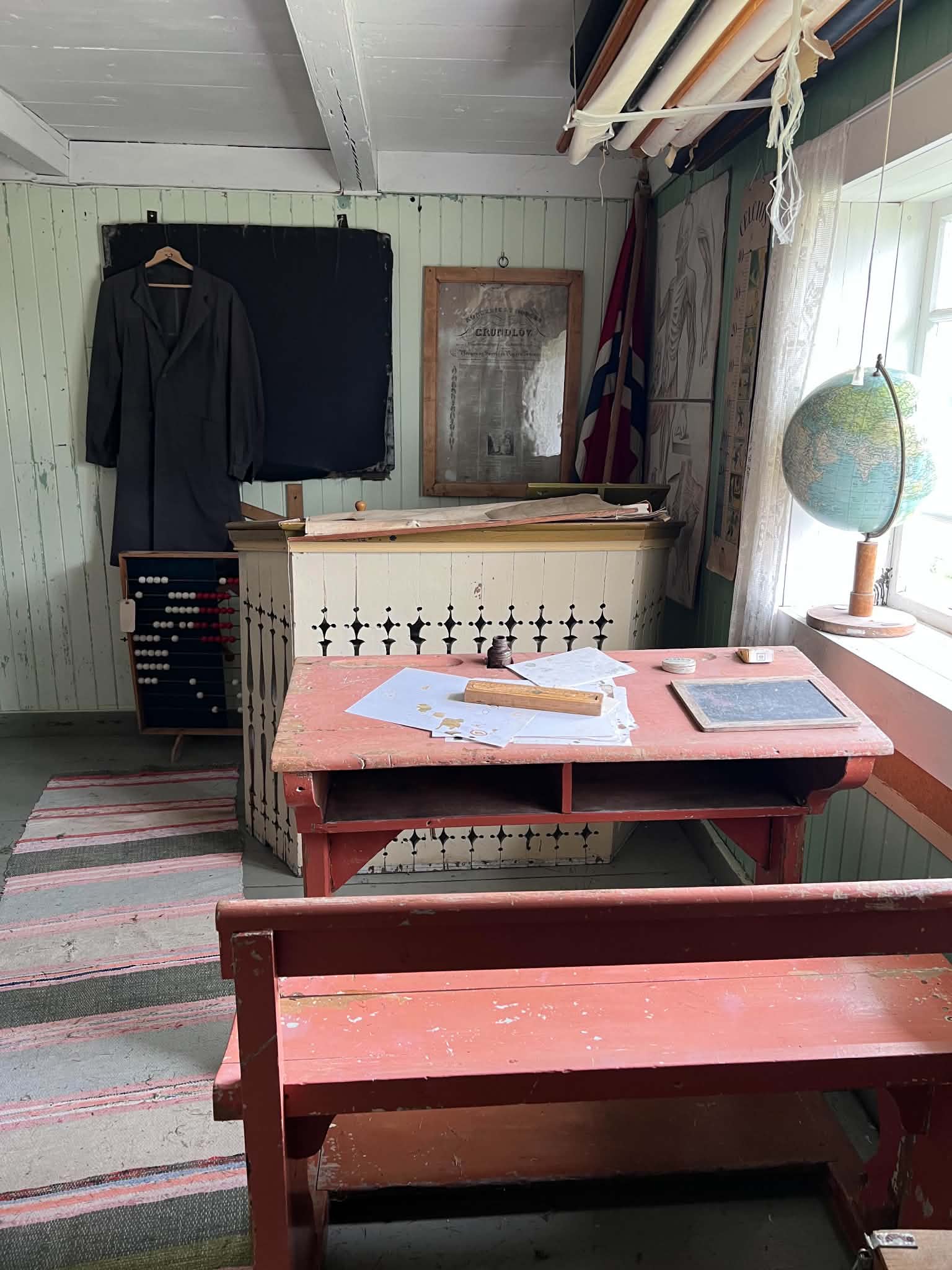 Preserved classroom with wooden desks, teaching materials and a globe
