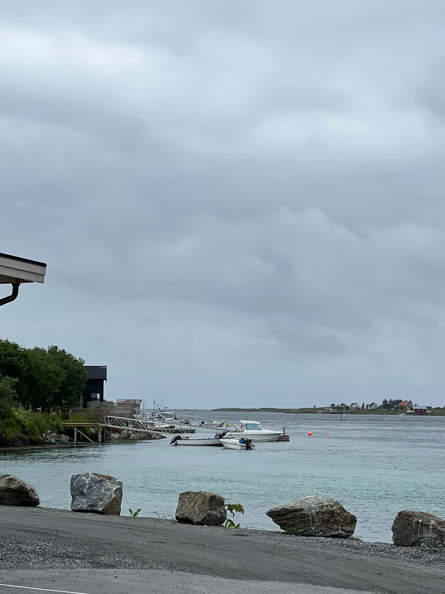 Small boats moored in a sheltered harbour on Herøy beneath low summer clouds.