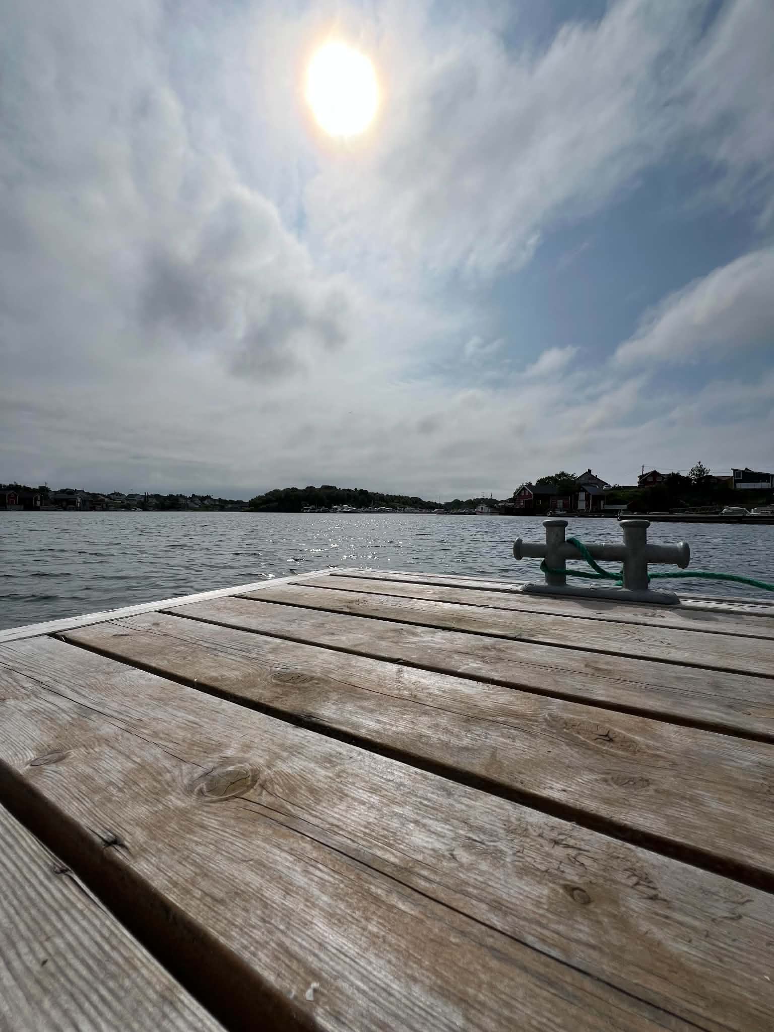 Sunlight over a wooden pier and sheltered coastal water on Herøy.