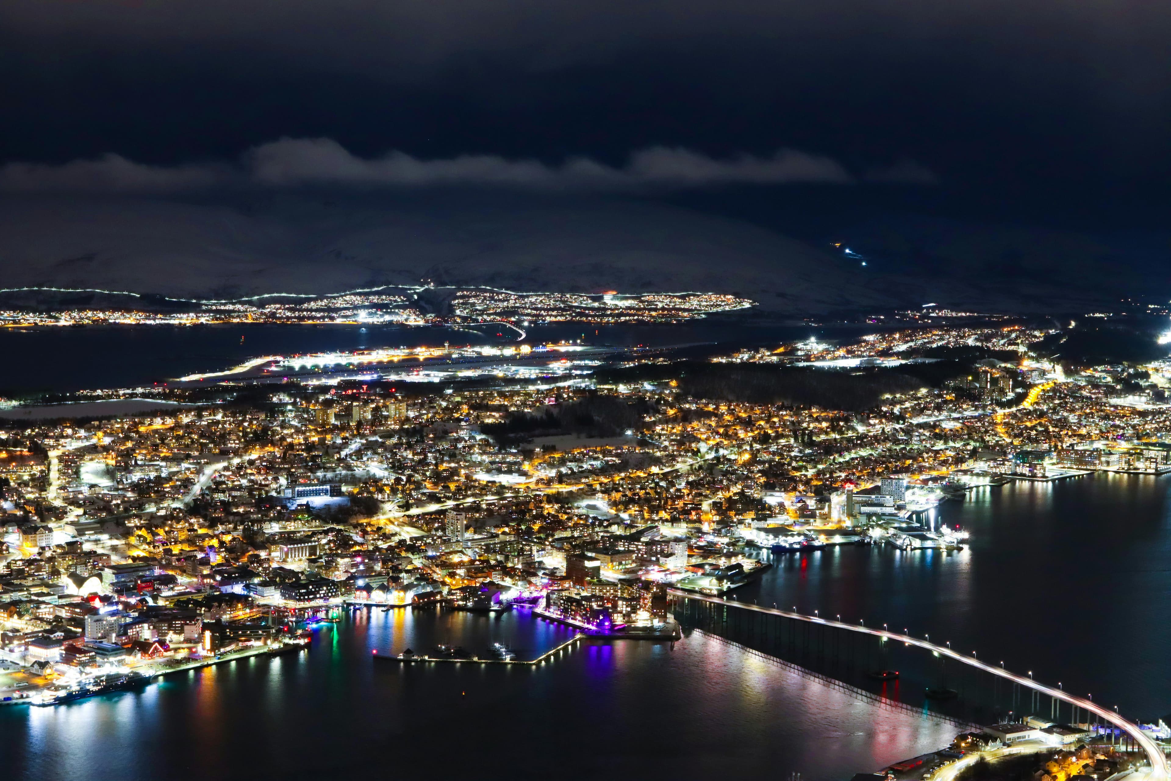 Tromso city lights surrounded by Arctic mountains at night